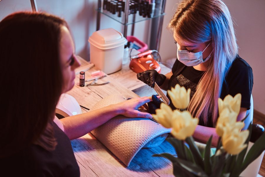 Nail master is working on client nails with nail file